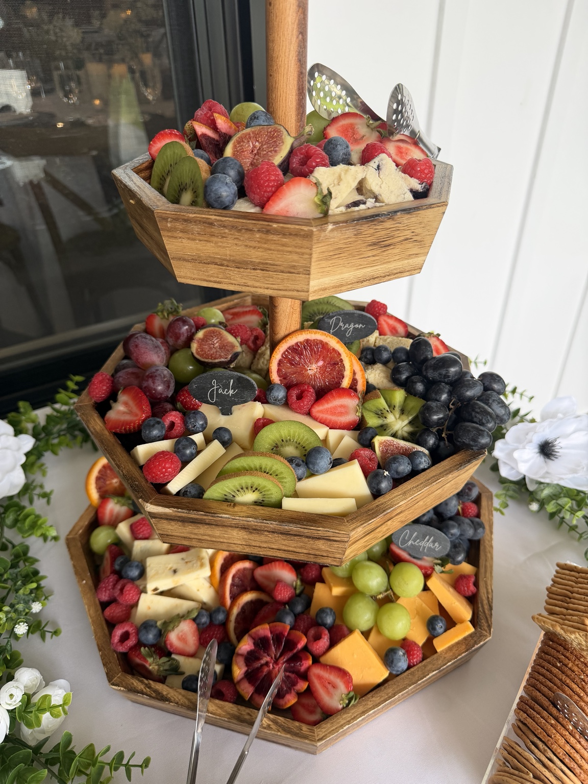 Tiered wooden display of fresh fruit and cheeses prepared by City Moose Catering